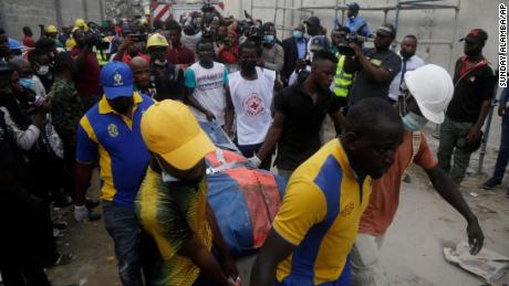 Equipes de resgate carregam um corpo no local de um prédio que desabou em construção em Lagos, Nigéria. 