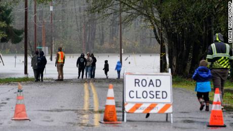 Pessoas em Sedro-Woolley, Washington, caminham em uma estrada que foi inundada na segunda-feira pelo transbordante rio Skagit.