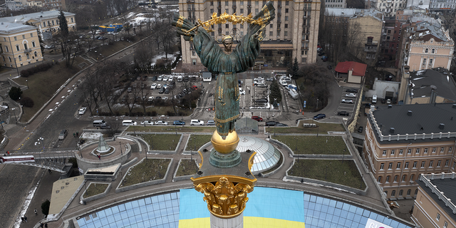 O Monumento da Independência aparece sobre a Praça Maidan, em Kiev, em frente à bandeira nacional ucraniana que foi exibida por ocasião do Dia da Unidade, em Kiev, na Ucrânia, na quarta-feira.
