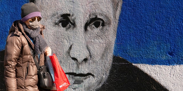 Uma mulher passa por um mural representando o presidente russo Vladimir Putin em Belgrado, Sérvia, sábado, 12 de março de 2022. 