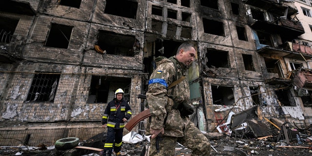 Soldados e bombeiros ucranianos inspecionam um prédio destruído após um ataque a bomba em Kiev, Ucrânia, segunda-feira, 14 de março de 2022. 