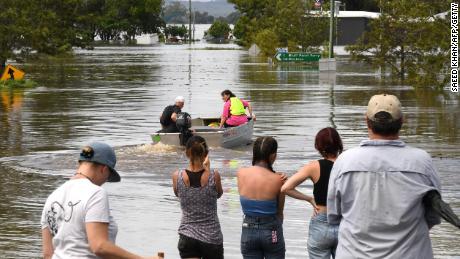Moradores ficam ao lado de uma rua inundada no subúrbio de Lawrence, a cerca de 70 quilômetros da cidade fronteiriça de Lismore, em Nova Gales do Sul, em 1º de março de 2022. 