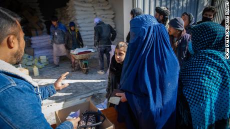 Uma mulher afegã recebe sua ração mensal de alimentos básicos para sua família de um ponto de distribuição do Programa Mundial de Alimentos no distrito de Jay Rais, a oeste de Cabul.