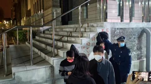 Um segurança tenta cobrir uma faixa de protesto contra o Zero Covid no campus da Universidade de Pequim, em Pequim.