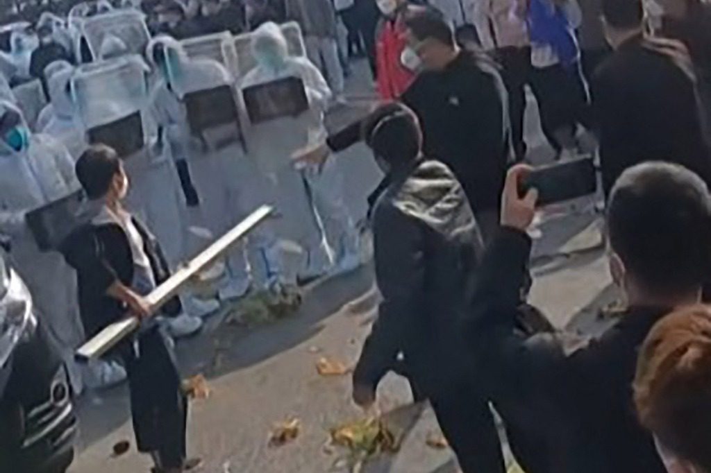 Um homem com uma longa vara enfrenta a polícia na China